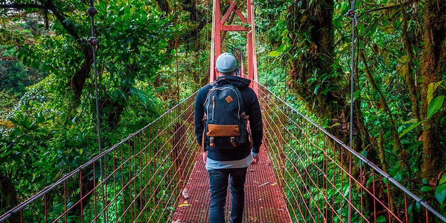 Mies kävelee yksin riippusillalla Monteverden sumumetsässä Costa Ricassa.