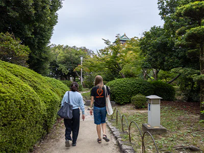 Japanilainen opas kulkee TourCompassin työntekijän kanssa Osakan linnalla Japanissa